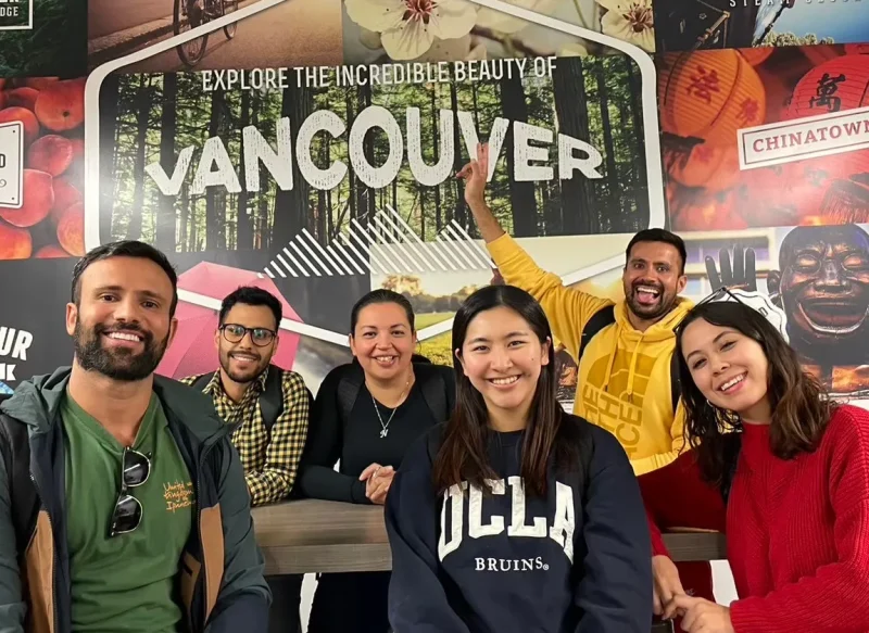 Vancouverの名所の写真の前で5人の友人と一緒にMisakiさんが笑顔で映っている。
