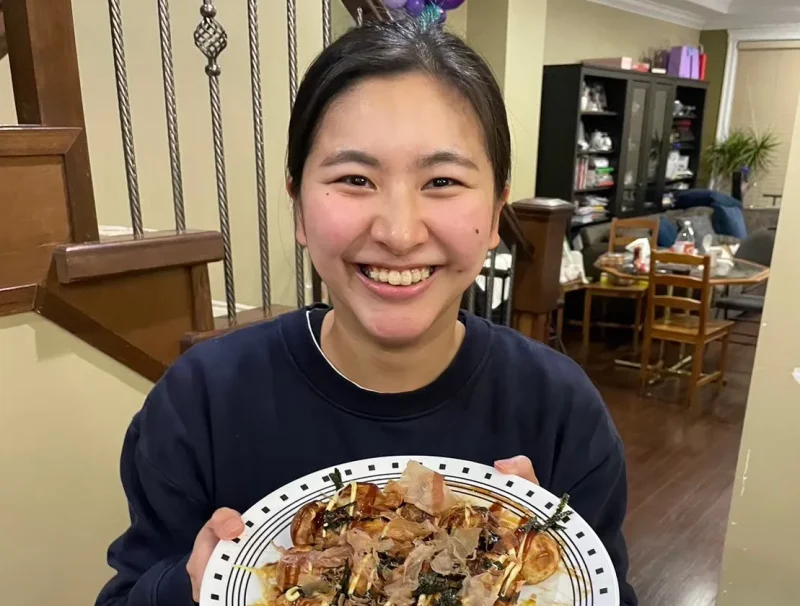 完成したたこ焼きを持って笑顔を見せている様子