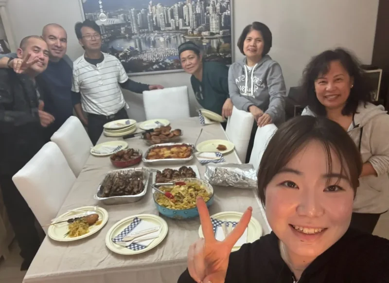 ホームステイファミリーの家での集合写真。テーブルの上にはご馳走が並んでいる