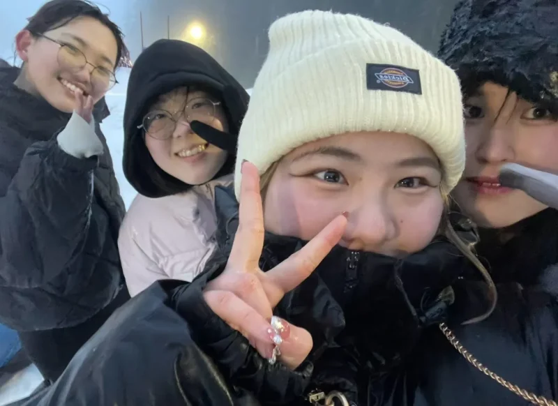 スノーアクティビティーの時の写真。屋外でダウンを着て友人と一緒に写っている