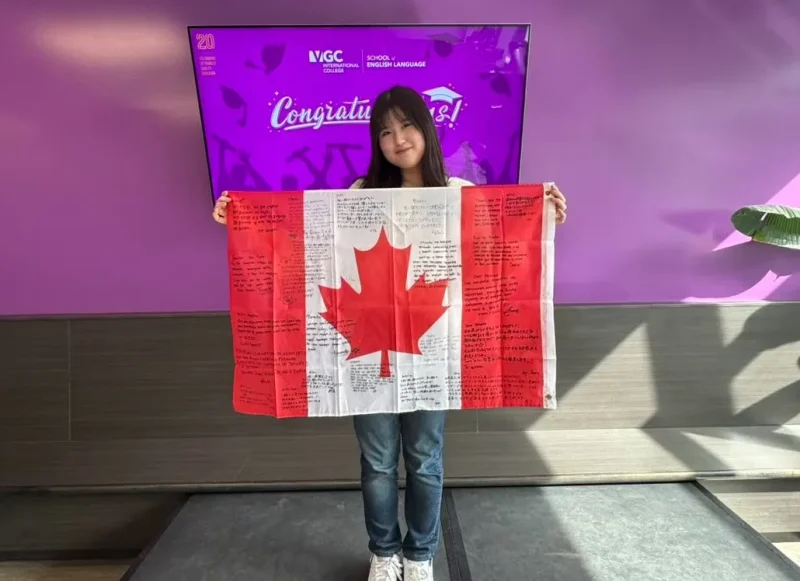 カナダ国旗にクラスメイトからもらった寄せ書きを手に写った写真